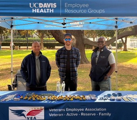 Picture of three VEA employee resource group board members standing at a booth at the Veterans Day parade in Sacramento